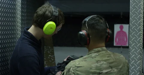 Instructor Showing Young Man How to Fire a Gun at a Range Stock Footage 45976323