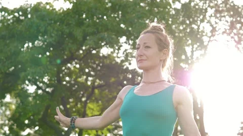 An instructor shows yoga exercises to his students in a park on a sunny day. Stock Footage 153138410