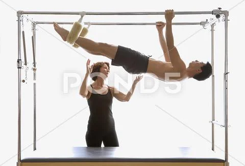 Instructor spotting man on exercise equipment Stock Photos