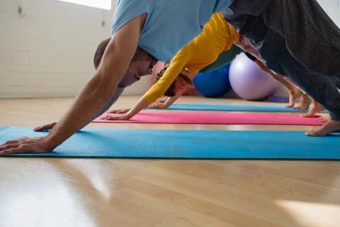 Instructor with students practicing downward facing dog pose at yoga studio Stock Photos
