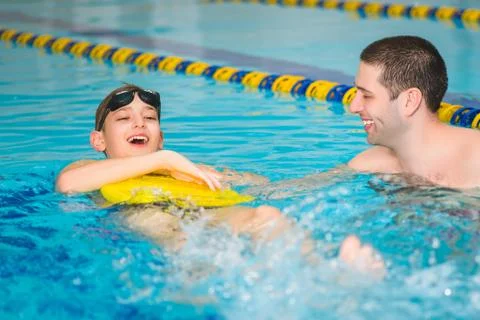 Instructor teaches the boy swimming in a pool Stock Photos