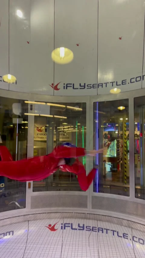 Instructor teaches man indoor skydiving. People fly in aero tube. Seattle, USA - Stock Footage 207983407