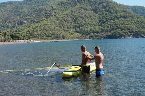 The instructor teaches the student how to windsurf. Windsurfing lessons. Stock Photos