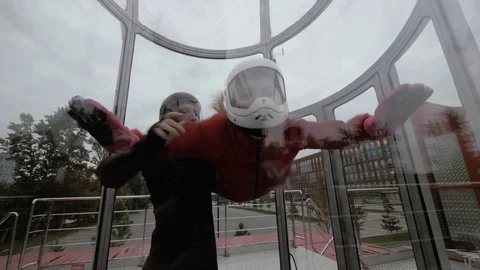 Instructor teaches woman skydiving in wind tunnel. Woman flying in wind tunnel Stock Footage 77152251