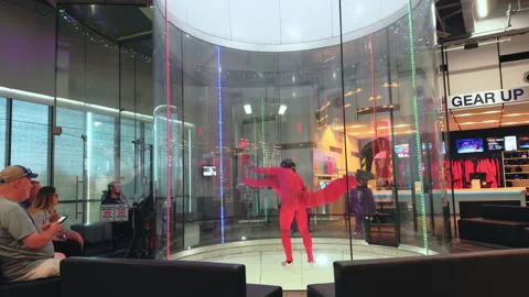 Instructor trains student floating horizontally inside skydiving wind tunnel Stock Footage 320264392
