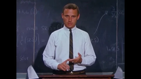 An instructor in white shirt and tie with his back to the blackboard gives a Stock Footage 117053400