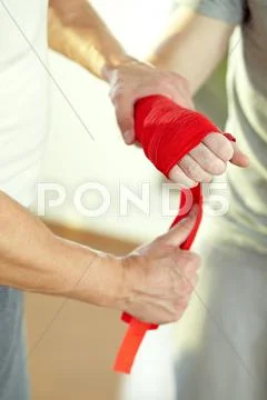 Instructor wrapping wrists of a man before boxing training Stock Photos