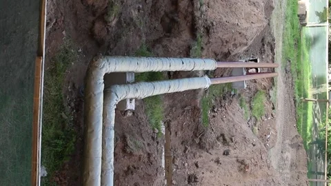Insulated main heating network pipelines in an open trench at a repair site. Stock Footage 345654172