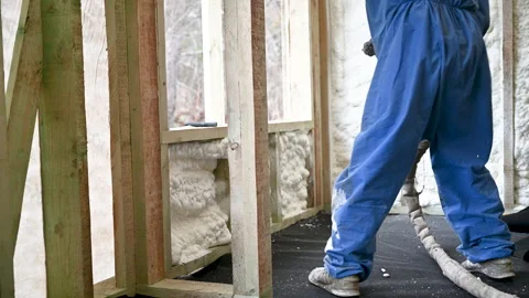 Insulation contractor applies foam to interior wall during building process Stock Footage 346741412