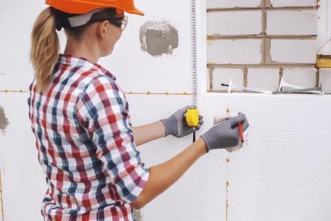 Insulation of the house with polyfoam. The worker is checking with the Stock Photos