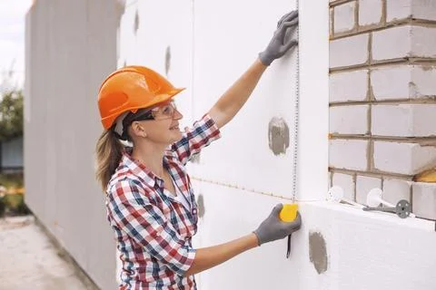 Insulation of the house with polyfoam. The worker is checking with the Stock Photos