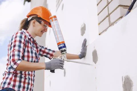 Insulation of the house with polyfoam. worker foaming joints of polystyrene Stock Photos