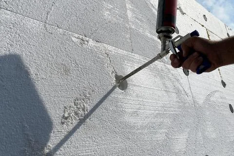 Insulation of the house with polystyrene foam, a worker insulates the house w Stock Photos
