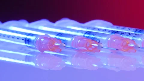 Insulin syringes rotate on a red background. Close-up on a white surface. Stock Footage 129095983