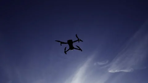 Intellegence spying drone hover on blue sky against shining sun, slow motion Stock Footage 308657578