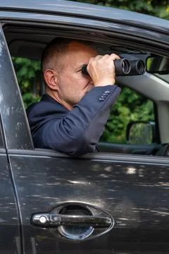 Intelligence agent conducting covert surveillance with binoculars 库存照片