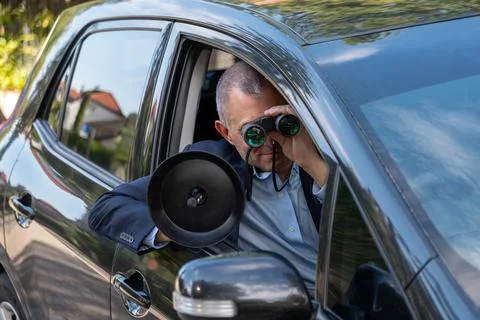 Intelligence agent conducting covert surveillance and listening from a car 库存照片