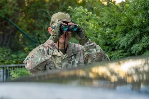 Intelligence scout monitors a distant target with optics while remaining co.. 库存照片