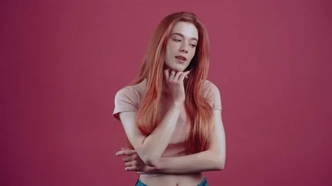 Intelligent 20-year-old redhead in pink casual T-shirt, isolated on pink Stock Footage 150368916