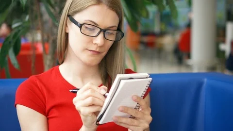 Intelligent smiling student in red t-shirt and glasses sitting in cafe and Stock Footage 76271427