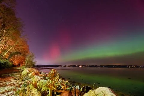 Intense Aurora Borealis Display Over Rocky Baltic Sea Coastline and Distant.. Stock Photos
