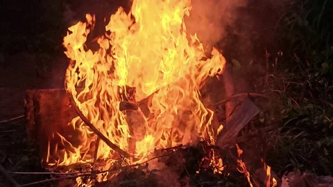 Intense blaze consuming an object outdoors at night; bright orange and yellow Vídeos de archivo 317779979