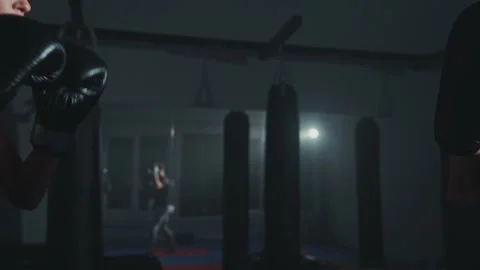 Intense boxing training session in a dimly lit gym featuring a determined 스톡 동영상 284413428