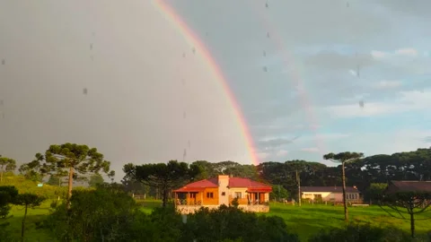 Intense double rainbow with sun and rain on landscape with a house in the middle Stock Footage 252224614