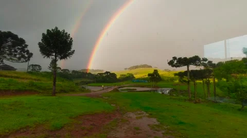 Intense double rainbow with sun and rain on landscape Stock Footage 252224622