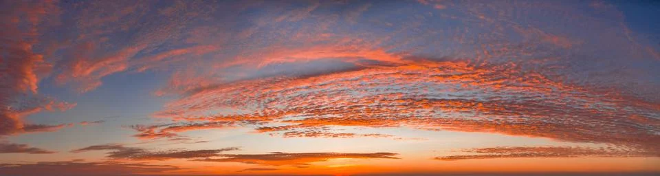 Intense dramatic panoramic sunset with cirrus clouds illuminated by red sunbe Stock-Fotos