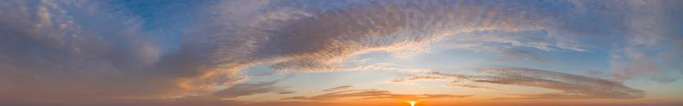 Intense dramatic panoramic sunset with cirrus clouds illuminated by golden ra Fotos de archivo