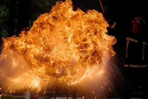 Intense Fire Burst. Dramatic close-up of a firefighter managing a large, intense Stock Photos
