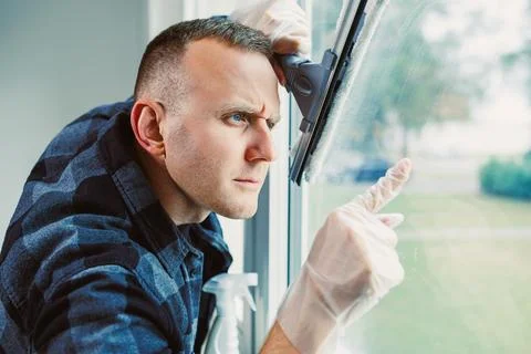 Intense focus during window cleaning in a bright modern home on a sunny day Stock Photos