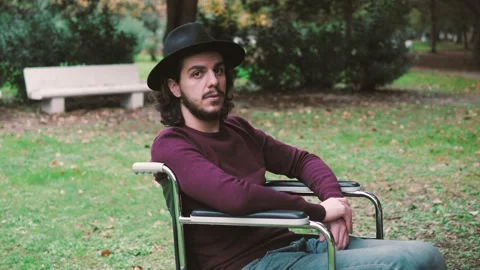 Intense gaze - young man using wheelchair alone at the park stares at camera Stock Footage 166229823