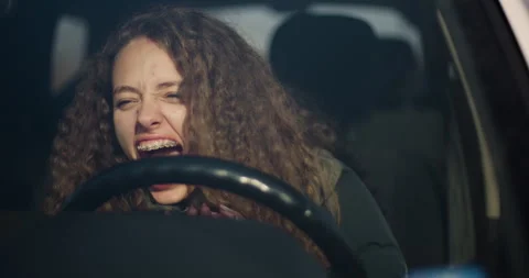 Intense image of a curly-haired young woman with braces screaming and gripping Stock Footage 322875143