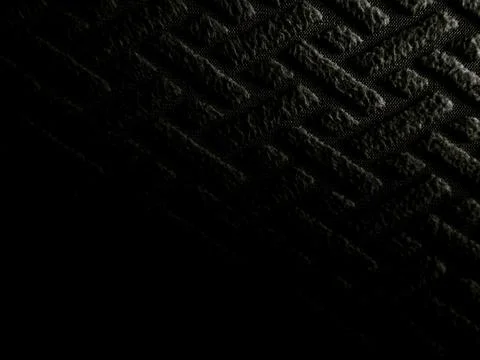 Intense macro capturing dramatic texture of deep black rubber mat with raised 스톡 사진
