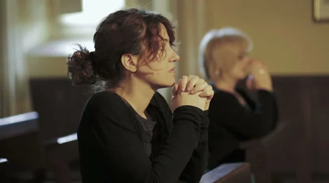 Intense prayer of two women in a church: religion, faith, devotion, Catholics Stock Footage
