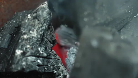 Intense red center visible within fractured black charcoal surface. Studio Stock Footage 341662708