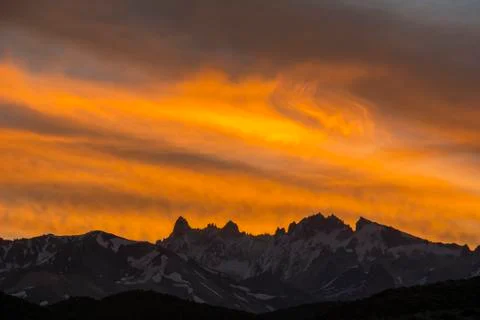 Intense red sunset over a distant range of sharp snowy mountain peaks Stock Photos