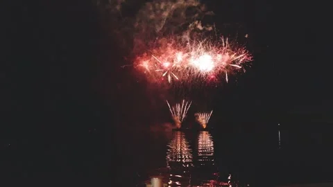Intense sequential fireworks display with flashing silver sparks over dark sea Stock Footage 340632815
