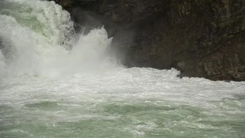 Intense slow-motion waterfall with churning white water and large brown rock.   Stock Footage 138911534