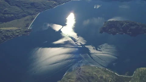Intense sun bouncing off blue lake with aerial rotation Stock Footage 155493347