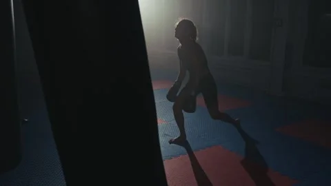Intense training session in a dimly lit gym by a dedicated athlete on a colorful Stock Footage 285150634