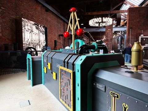 Interactive industrial engine exhibit with colorful controls and visitors i.. Foto stock
