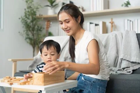 Interactive Learning. Mother and child playing with wooden blocks at home. Stock Photos