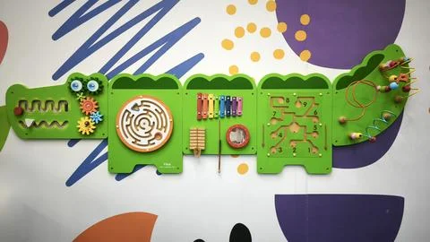 Interactive wall-mounted sensory play panel for kids, shaped like a crocodile Foto stock