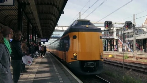 Intercity train pulling into station beside outdoor platform, passengers waiting Stock Footage 169097046