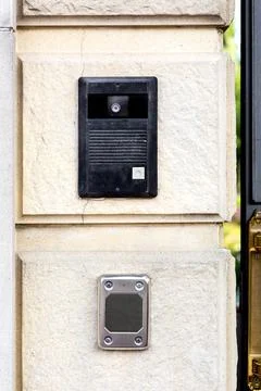 An intercom with a call button and a camera with microphone on stone wall. Stock Photos