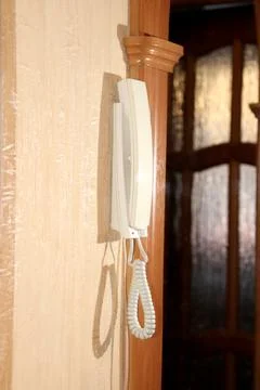 The intercom handset hangs on the wall - view of the device in profile Stock Photos