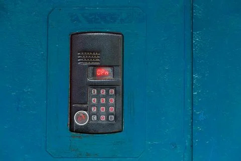 An intercom on old painted blue steel surface with a keypad, digital display and Photos